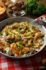 Roasted mushrooms, chicken and cheese gratin in pan, on wooden background