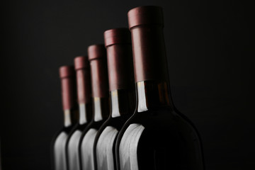 Wine bottles in a row on black  background, close up