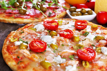 Delicious tasty pizzas with ingredients on table, closeup