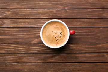 Cup of coffee on wooden table, top view