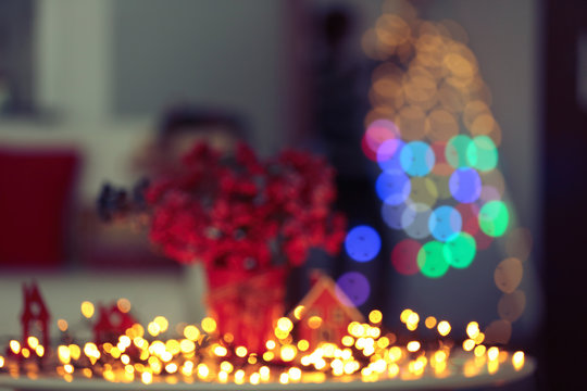 Blurred bouquet of red berries with light garland on a table