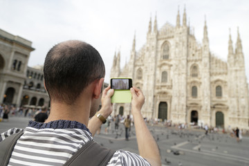 Fototapeta na wymiar Man taking a picture of the Duomo di Milano (Milan Cathedral) a with a smartphone, Milan, Italy