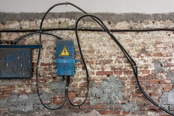 Old brick wall with electric wires and a control board