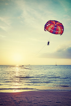 Retro stylized parasailing at sunset, summer adventure concept.