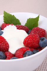 fresh raspberries and berry with cream and sugar on a bowl