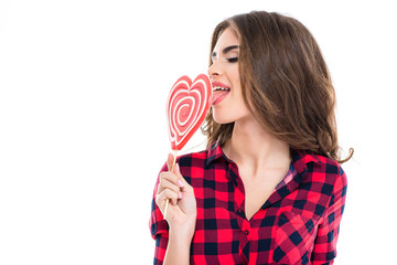 Closeup of charming young woman eating heart shaped candy