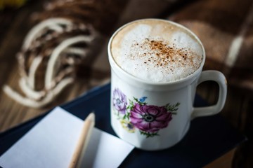 Cup of cappuccino with blurred paper and pencil horizontal