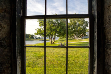 On The Inside Looking Out. Sunny outdoor scene framed by a dark and dilapidated window frame. The property is located on a state owned building open to the public. It not a private residence.