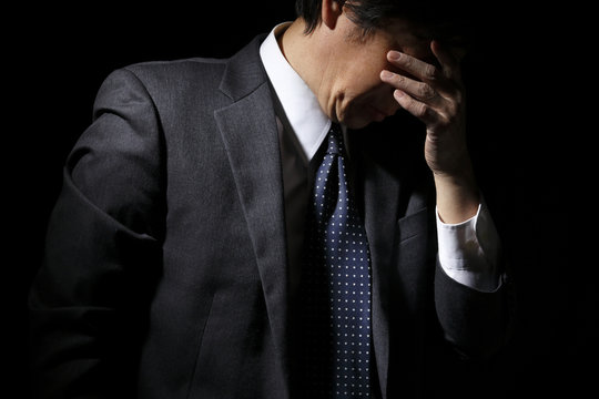頭を抱える中年ビジネスマン