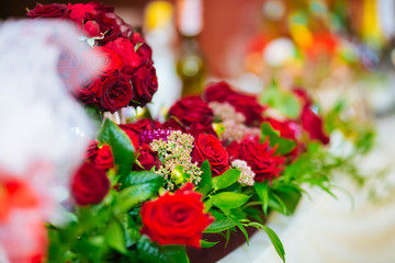 Beautiful floral decoration of the wedding banquet table: a bouquet of roses, pearl strands, clear vases