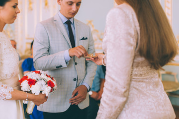 Gentle romantic happy couple exchanging wedding rings in wedding palace