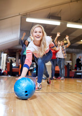 happy young woman throwing ball in bowling club - obrazy, fototapety, plakaty