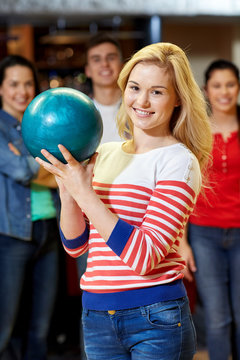 happy young woman holding ball in bowling club