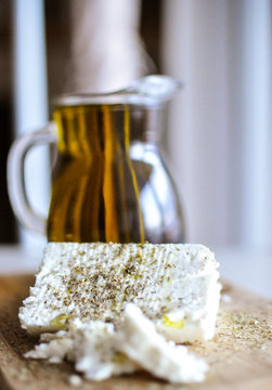 feta cheese(Greek cheese) slices on a wooden serving board  and a bottle of olive oil in nature light