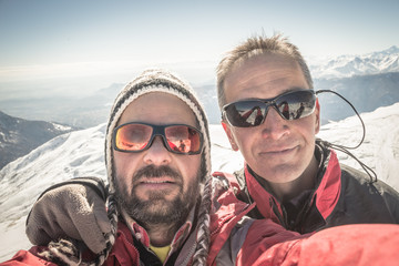 Fototapeta premium Selfie of two alpinists on the mountain top in winter