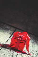 Red gift box tied with a scarlet ribbon with a bow on the old wo
