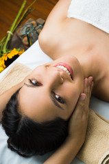 Obraz na płótnie Canvas Hispanic brunette model getting massage spa treatment, hands around womans head with eyes open smiling