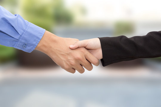 Business man and woman handshake on blur background