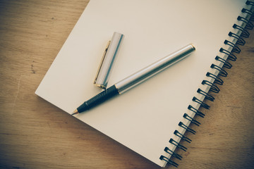 paper notebook and pen on a table with filter effect retro vinta