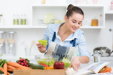 Photo sur Plexiglas Cuisinier jeune femme cuisine tous les soirs avec un répéteur du livre de cuisine