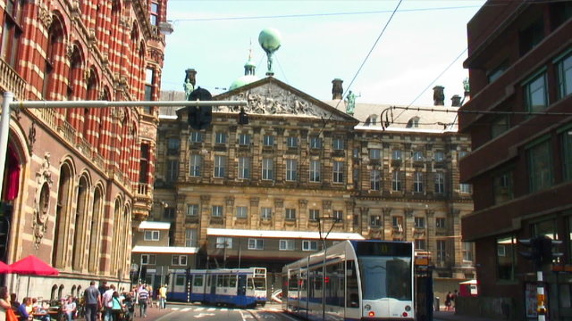 Royal Palace in Amsterdam with commuter trams in the street.