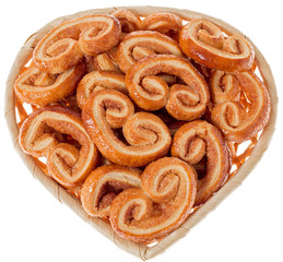 Puff pastries with cinnamon in a straw basket in the shape of a heart. A gift for Valentine's Day.