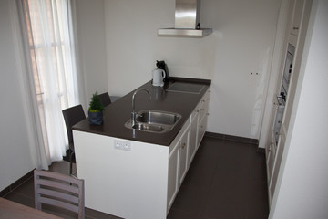 Kitchen modern style. Combined kitchen and dining room with black and white walls, black furniture and white dining table. 3D render