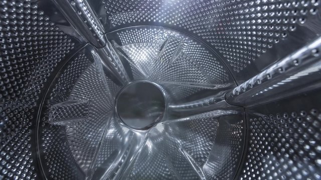 Camera tracks into the washing machine drum in motion.