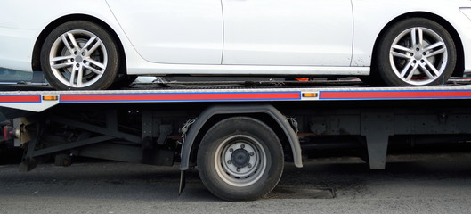 Fototapeta na wymiar Luxury white car transported on a truck