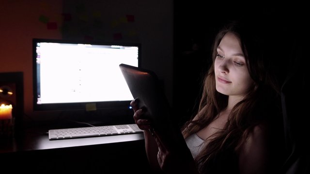 Teenage girl watching movie on tablet in bed at night