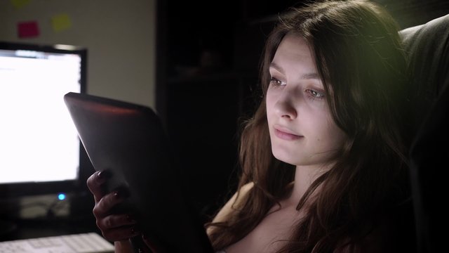 Teenage girl watching movie on tablet in bed at night