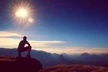 Slim tourist on the sharp peak of rock in rock empires park is watching over the misty and foggy morning valley to Sun