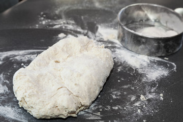 piece of fresh dough with blurred flour strainer