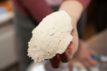 Hand holding piece of dough with selective focus