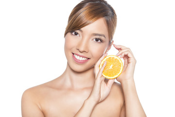 beautiful young asian woman with long hair, flawless skin and perfect make-up. Holding orange on isolated background