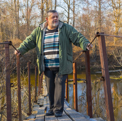 Senior man standing on a suspension bridge over Vorskla river in Ukraine