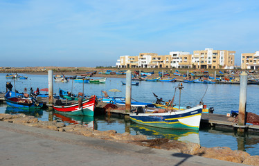 Fototapeta na wymiar Rabat, Morocco - December 26, 2015: New exclusive apartment buildings at Bouregreg Marina in Rabat. Traditional blue fishing boats in the foreground.