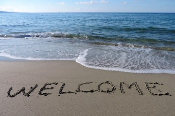 Inscription Welcome on wet sand. 