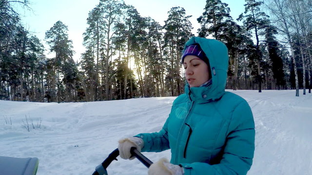 The girl with the baby in a carriage on walk in winter wood. 
