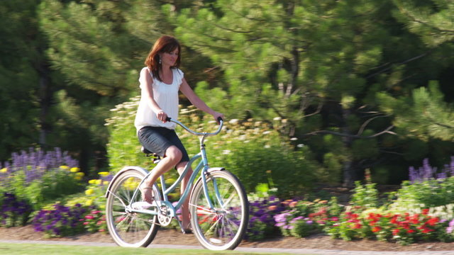 Young woman riding a bike through a beautiful garden.