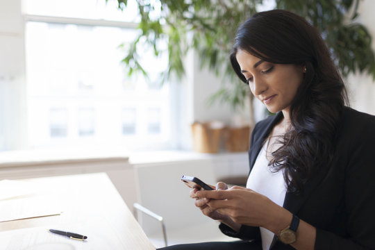 Young businesswoman using smart phone while working in office
