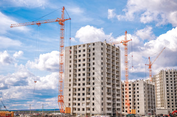 Fototapeta na wymiar Tall cranes and construction of building