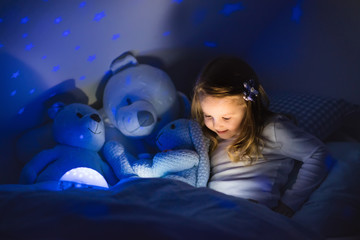 Little girl reading a book in bed