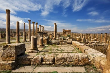 Sheer curtains Rudnes Algeria. Timgad (ancient Thamugadi or Thamugas). Row of columns at the forum and colonnade along Decumanus Maximus street terminated Trajan's Arch