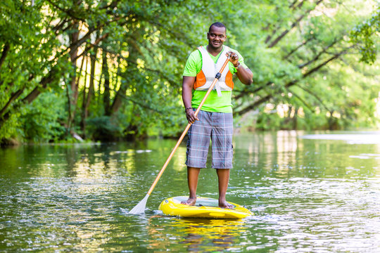 Mann beim Stehpaddeln auf SUP auf Fluss