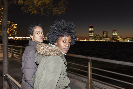 Portrait of two young women sitting by the river at night