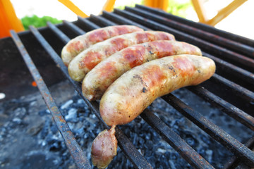 Pork - beef sausages on grill in the summer garden