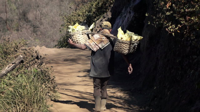 Ijen volcano, worker carrying heavy basket with sulfur, slow motion
