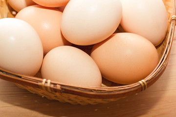 many eggs in a wicker basket on a wooden table