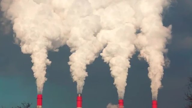Fast motion of smoke or steam columns from four red stacks on blue background. Dioxide carbon and warm, exhausting with the industry chimneys in atmosphere. Dramatic view with time lapse effect.